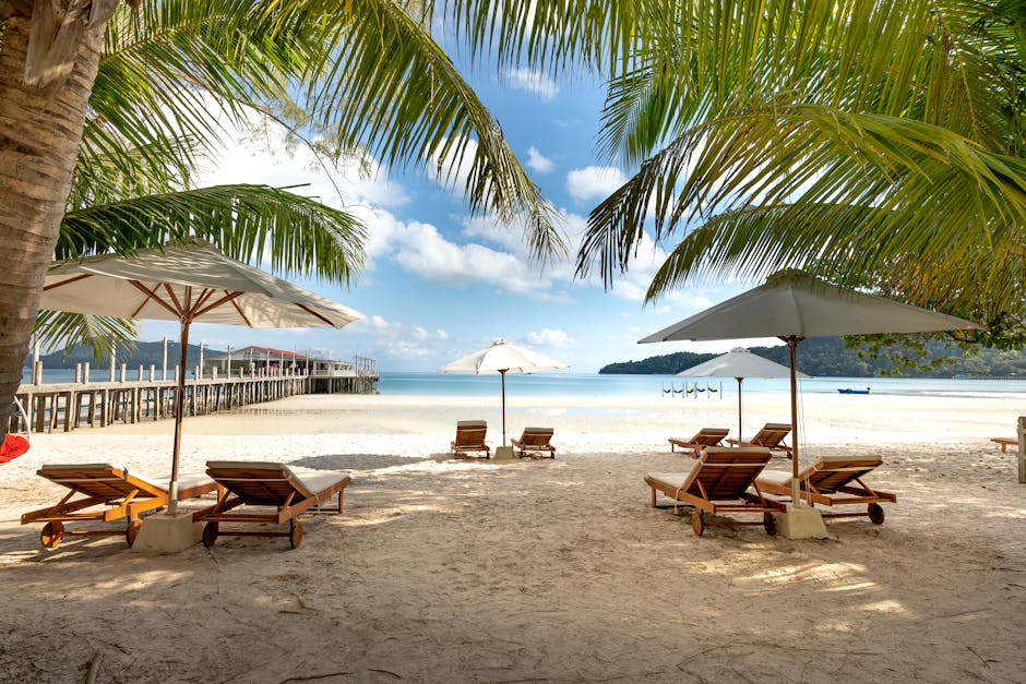 Relaxing tropical beach view with palm trees, umbrellas, and lounge chairs on a sunny day